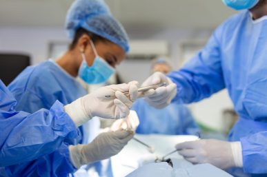 Shot in the Operating Room, Assistant Hands out Instruments to Surgeons During Operation. Surgeons Perform Operation. Professional Medical Doctors Performing Surgery.